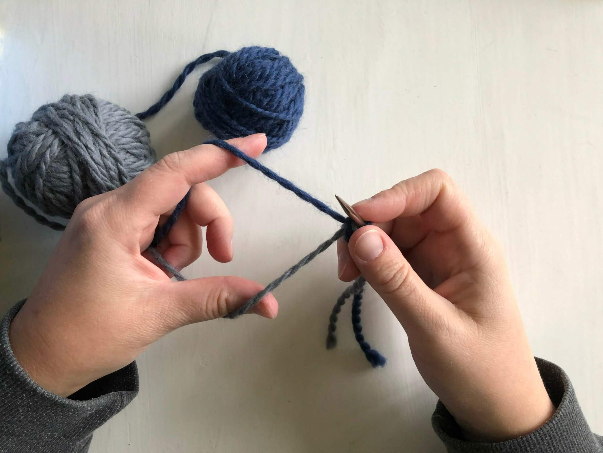 Image shows how to hold the yarn and needle when dong the Latvian braid cast on