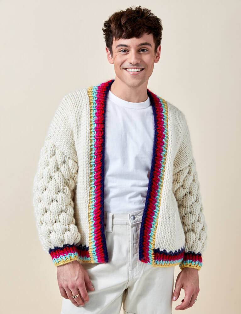A picture of Tom Daley wearing his own design, Cuddle cardigan, sold as a knitting kit. 